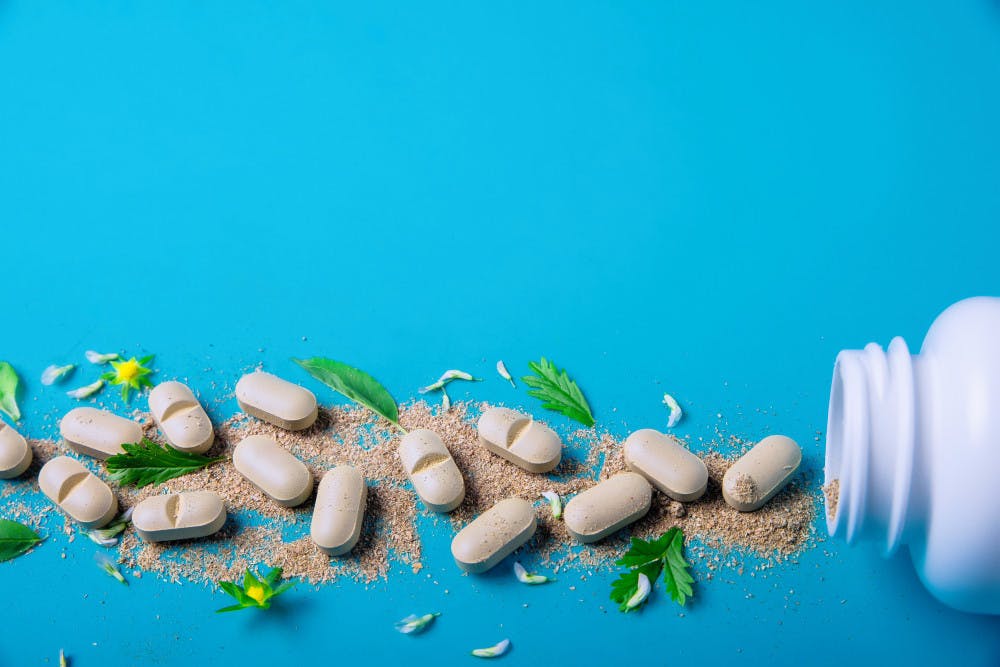 Blue background with pill box lying flat and pills coming out of it 